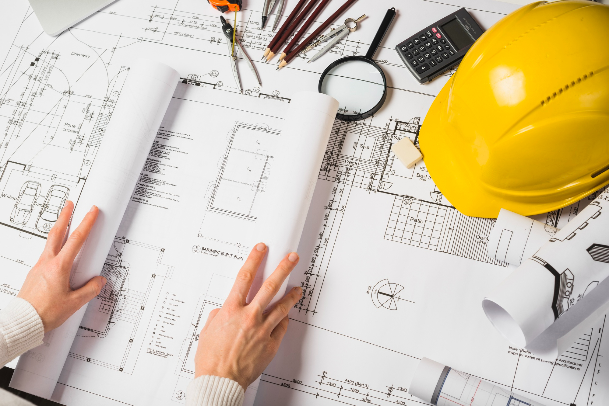 planos sobre la mesa con casco de obra